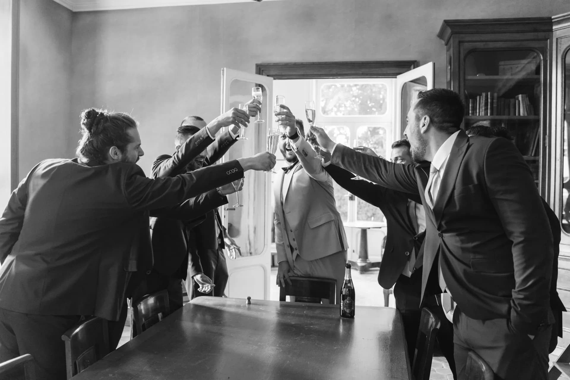 Haie d'honneur des invités bras levés à l'entrée des mariés dans la salle de réception, en noir et blanc