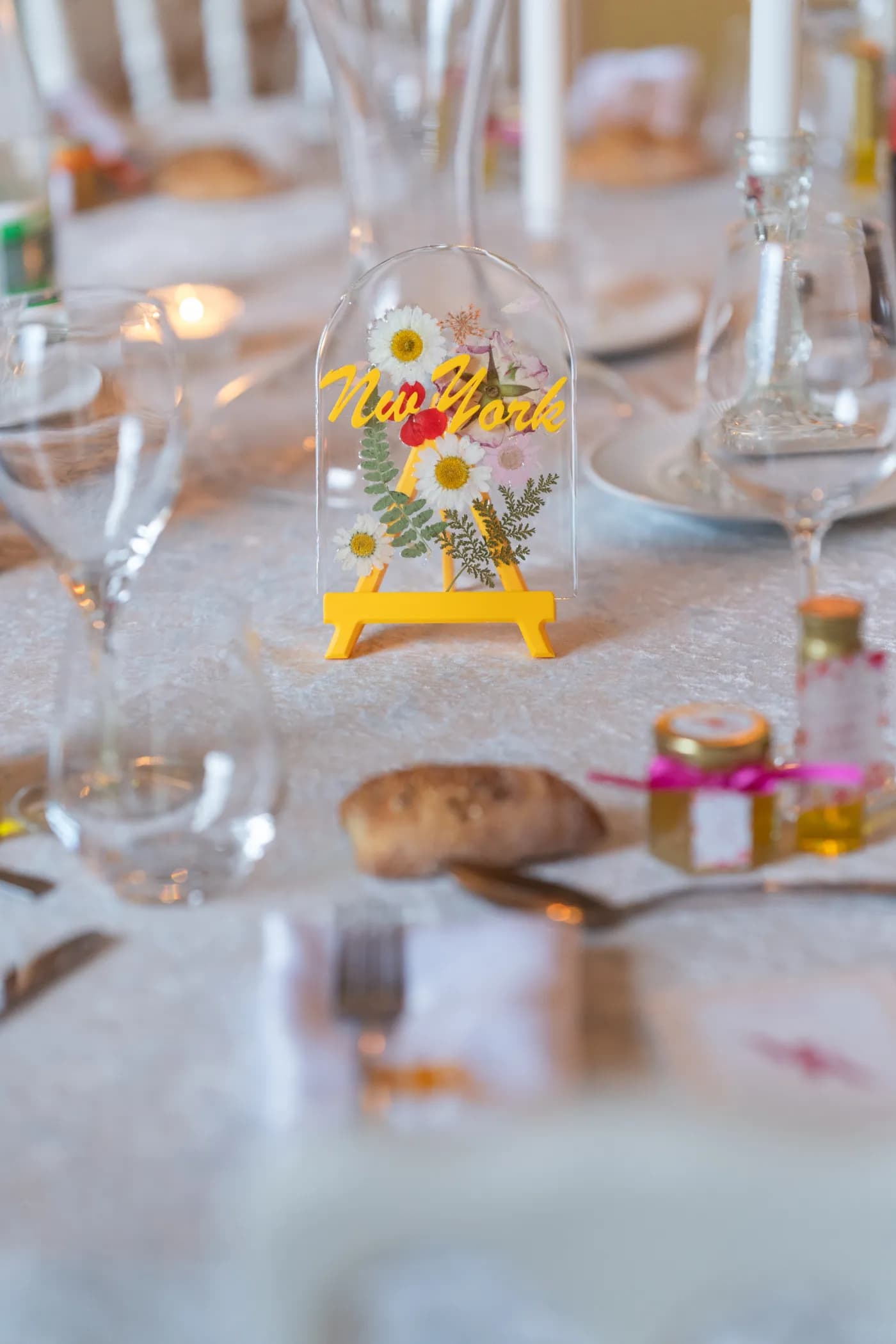 Nom de table calligraphié sur chevalet au milieu des verres et des menus d'un couvert de réception